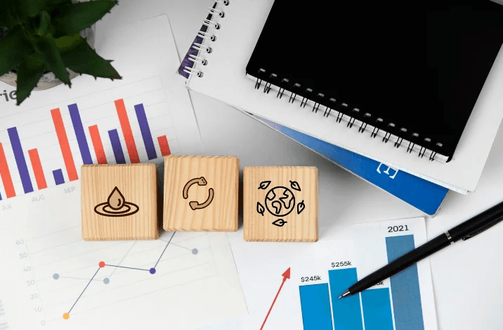 Wooden blocks with sustainability icons next to charts and graphs